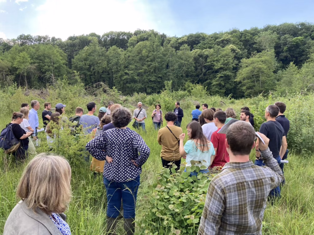 Photo d'un groupe de personne dans un champs avec une forêt en fond